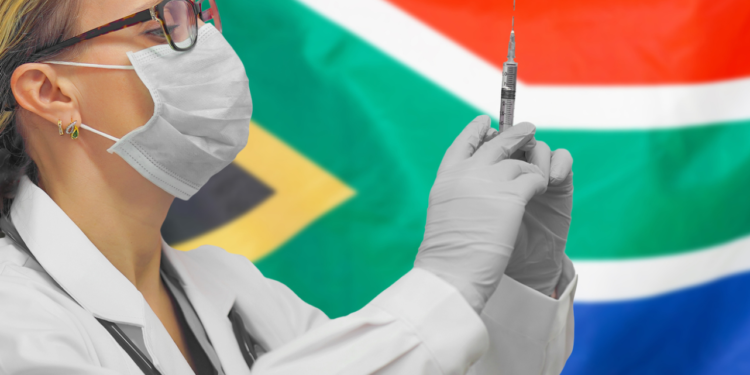 Getty Images | A doctor holding syringe for vaccination against COVID-19, in front of a South African flag.