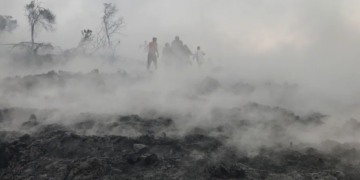 People are seen walking near smoldering ashes early morning in Goma in the East of the Democratic Republic of Congo on May 23 following the eruption of Mount Nyiragongo | AFP