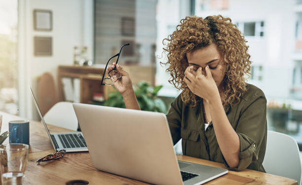 Shot of a young woman suffering from stress while using a computer at her work desk