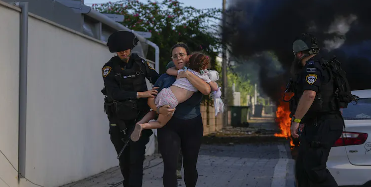 Israeli police officers evacuate a woman and child from a site hit by a rocket in Ashkelon, southern Israel.