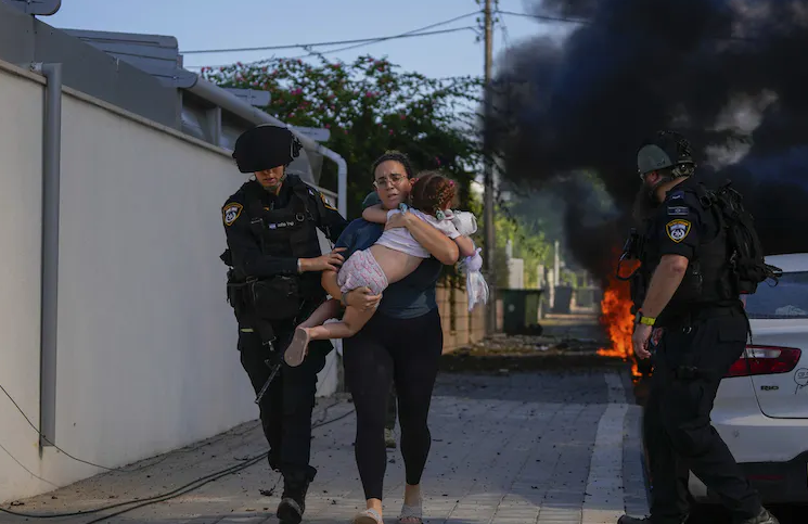 Israeli police officers evacuate a woman and child from a site hit by a rocket in Ashkelon, southern Israel. 
