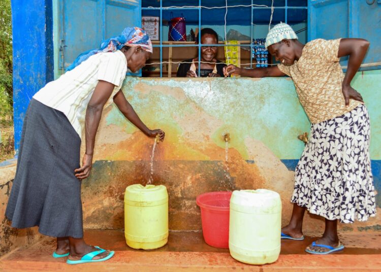 A photo showing women fetching water at a point by the USAID. 