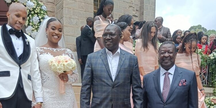 Prime CS Musalia Mudavadi, Cooperative CS Simon Chelugui poses for a photo with the bride and bride groom at the wedding's venue. 