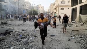 A Palestinian carries a child after an Israeli air strike in Khan Yunis in the southern Gaza Strip on 14 October 2023 | AFP