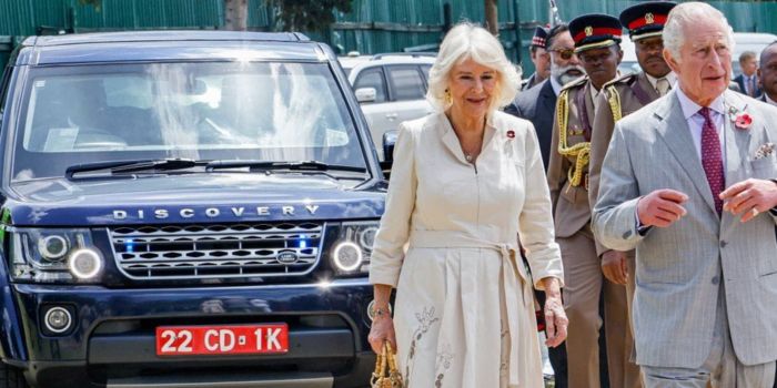 King Charles (right) and Queen Camilla of the United Kingdom walk in front of the vehicle they used during their visit in Kenyan on October 31 with red number plates