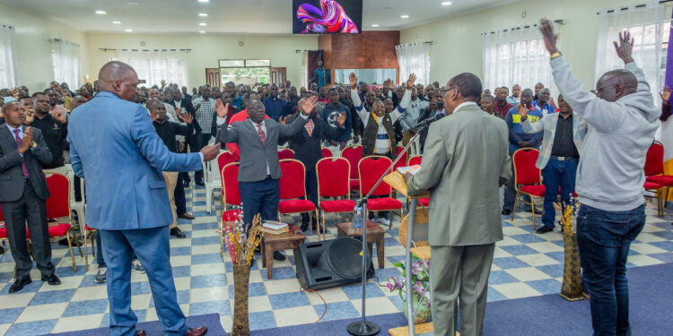 Dr Joe Kayo (center) speaks during a passt church service in Kenya. 