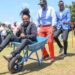 Media personality Anto Neosoul (siited on the wheelbarrow) enjoys a wheelbarrow ride with President William during the 2022 elections cam[paigns in Karen.