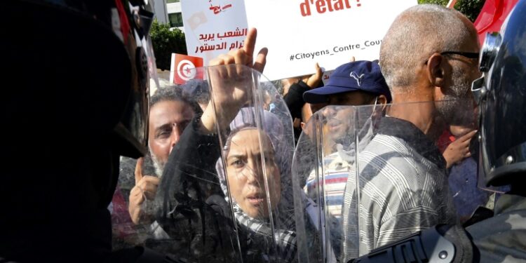 Tunisians face riot police during a rally against President Kais Saied along Bourguiba Avenue in the capital Tunis, where some complained about alleged police intimidation | AFP