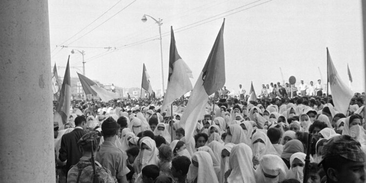 Algerian soldiers, veiled women and children, wave National Liberation Front (FLN) and now independent Algerian state flags on August 03, 1962 | AFP